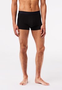 Boxer shorts en coton noir avec une taille douce et extensible, conçus pour le confort et une coupe moderne, avec des détails de couture minimalistes.