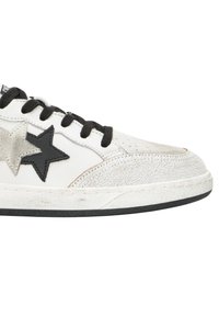 Sneaker di pelle bianca con lacci neri, presenta applicazioni a forma di stella nere e grigie e una punta con texture screpolata. Suola in gomma nera.
