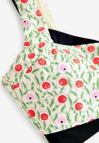Floral-patterned bikini top featuring cherry and flower designs in red, green, and pink. Solid black band at the bottom. Smooth fabric finish.