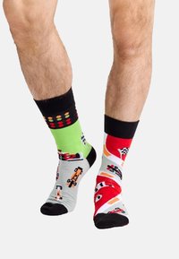 Calzini colorati con design a tema corsa. Un calzino è verde con punti colorati, l'altro è rosso con vari modelli di veicoli.