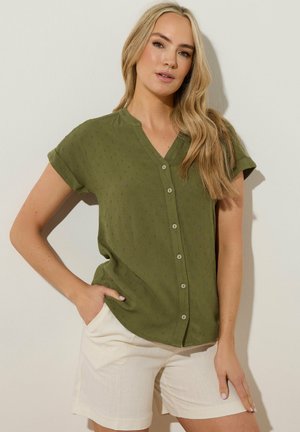 Olive green short-sleeve shirt with a V-neckline and button front; features a textured fabric and subtle pattern; paired with beige shorts.