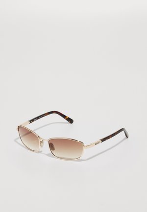 Gafas de sol con montura de metal dorado y lentes marrones degradados. Detalles de carey en las varillas; la marca "QUAY" está impresa en una de las varillas.