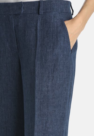 Dark blue, linen blend trousers with a relaxed fit, featuring side pockets and a smooth texture. Notable front pleats add dimension.