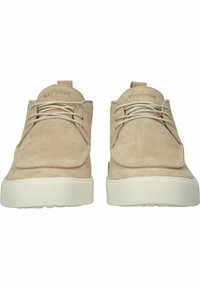 Zapatos de ante beige con un diseño de puntera redondeada y suela de goma blanca de perfil bajo. Cuenta con un cordón minimalista y un upper cosido.