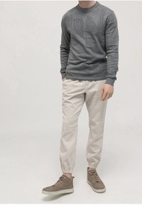 Gray knit sweater with textured patterns, paired with light beige tapered pants and gray high-top sneakers. Outfit is casual and modern.