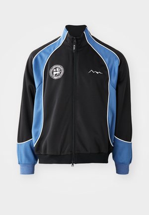 Black and blue athletic jacket, zippered front, contrasting white piping, logo patch on chest, ribbed cuffs, smooth synthetic fabric.