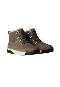 Stivale in suede marrone con fodera in pelliccia sintetica bianca, occhielli metallici e lacci grigi. Presenta una suola intermedia bianca e una suola esterna in gomma nera testurizzata.
