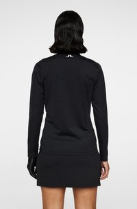 Langærmet sort atletiktop med rund halsudskæring. Har struktureret stof og et logo på ryggen. Stylet med en matchende nederdel.