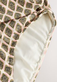 Plavky s geometrickým vzorom v zlatej a námorníckej modrej na svetloružovom pozadí. Hladká biela vnútorná podšívka s prešitými okrajmi.