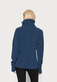 Navy blue fleece jacket with high collar, long sleeves, and relaxed fit. Features soft texture and no visible fasteners.