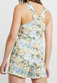 Floral romper featuring a blue-green landscape print with orange flowers and palm trees. Cross-back straps and a fitted waist design.