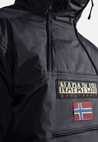 Black, lightweight jacket with a high collar, half-zip, embroidered logo, and flag patch featuring blue and red. Smooth, shiny material.