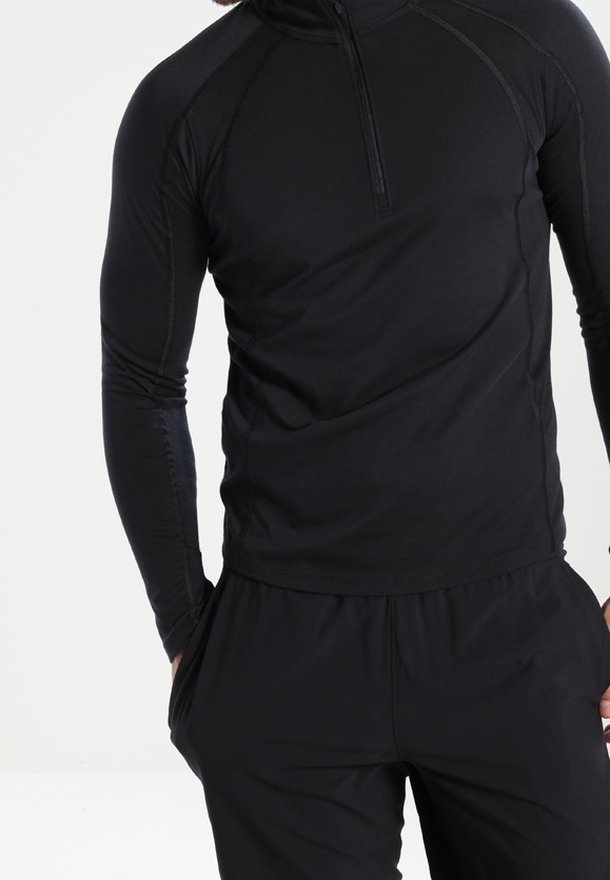 Svart, långärmad träningsskjorta med halvdragkedja och raglanärmar, tillverkad av ett mjukt och stretchigt material. Minimalistisk design.