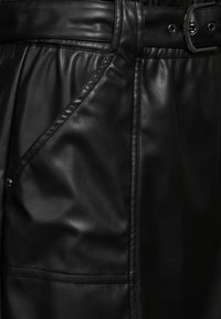 Gonna in pelle nera con una trama liscia, dotata di vita alta, cintura larga e tasche angolari con dettagli di cucitura discreti.