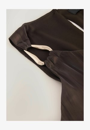 Tummanruskea kangas, jossa on sileä rakenne, metalliset yksityiskohdat ja rypytetty viimeistely reunassa.