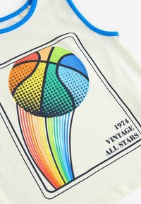 Licht crèmekleurig tanktop met een blauwe halslijn. Bevat een kleurrafisch van een basketbal met halftoon stippen en een regenboogstaart, gelabeld "1974 VINTAGE ALL STARS."