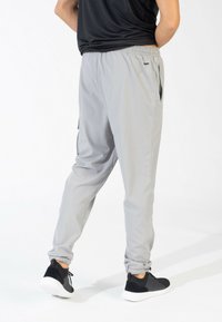 Gray athletic pants with elastic waistband, cuffs, and side pockets; made of lightweight fabric; paired with black sneakers.