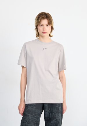 Light gray cotton t-shirt with a crew neck and short sleeves. Features a small black Nike logo on the chest. Smooth texture.