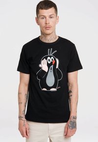 Sort t-shirt med et tegneserie-muldvarp grafik. Muldvarpen har en grå mave, rød-orange næse og hvide detaljer. Korte ærmer og rund halsdesign.