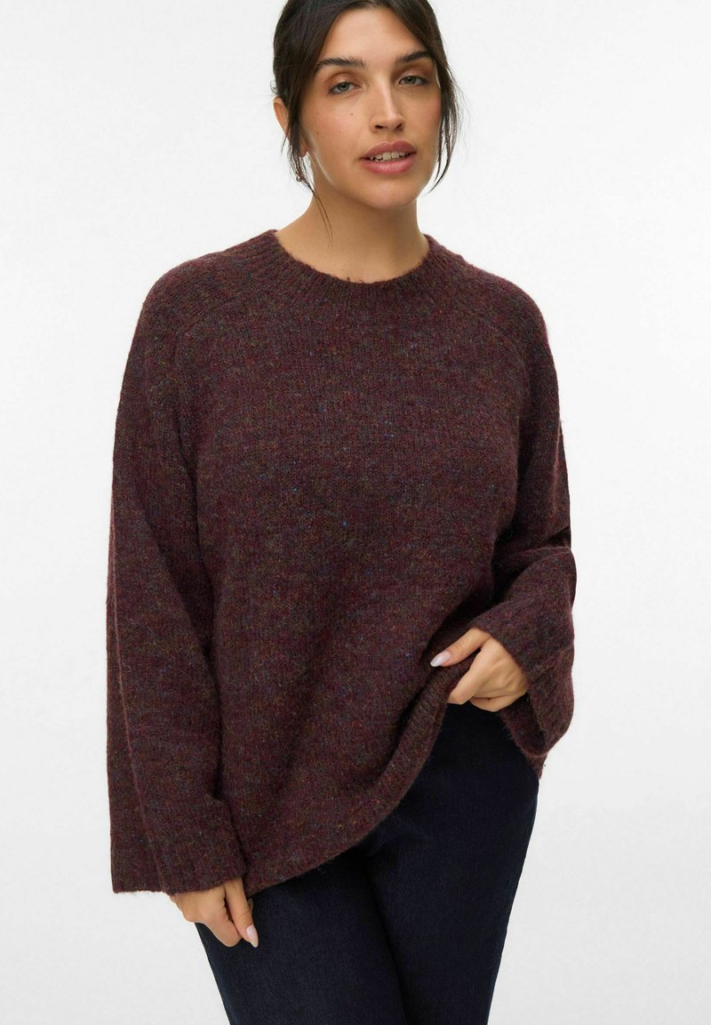 Pull en tricot bordeaux avec un col rond, coupe ample et manches longues. Fabriqué en matériau texturé avec des variations de couleur subtiles.