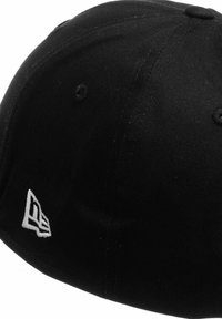 Schwarze Kappe aus Stoff mit strukturiertem Design. Verfügt über ein weißes, gesticktes Logo an der Seite sowie Belüftungslöcher auf der Krone.