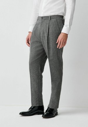 Gray plaid trousers with a tailored fit, pleated front, and belt loops, paired with polished black shoes. Smooth wool blend texture.
