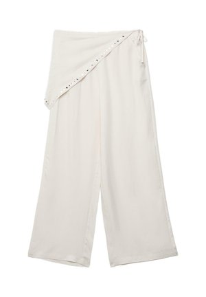 Široke krem hlače s asimetričnim preklopom u struku, pričvršćene bočnim trakama i ukrašene malim metalnim nitnama.