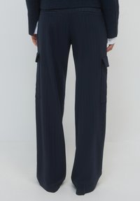 Marineblau gestreifte Hose mit entspannter Passform, seitlichen Cargo-Taschen, maßgeschneidertem Design und glatter Stofftextur.