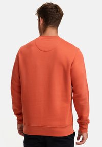 Sudadera naranja de manga larga, con escote redondo y un acabado texturizado. Presenta un corte clásico y puños y dobladillo acanalados.
