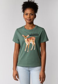 Groene katoenen t-shirt met een gedrukt afbeelding van een hert met witte vlekken, naast de tekst "Underground RESISTANCE" in het zwart.
