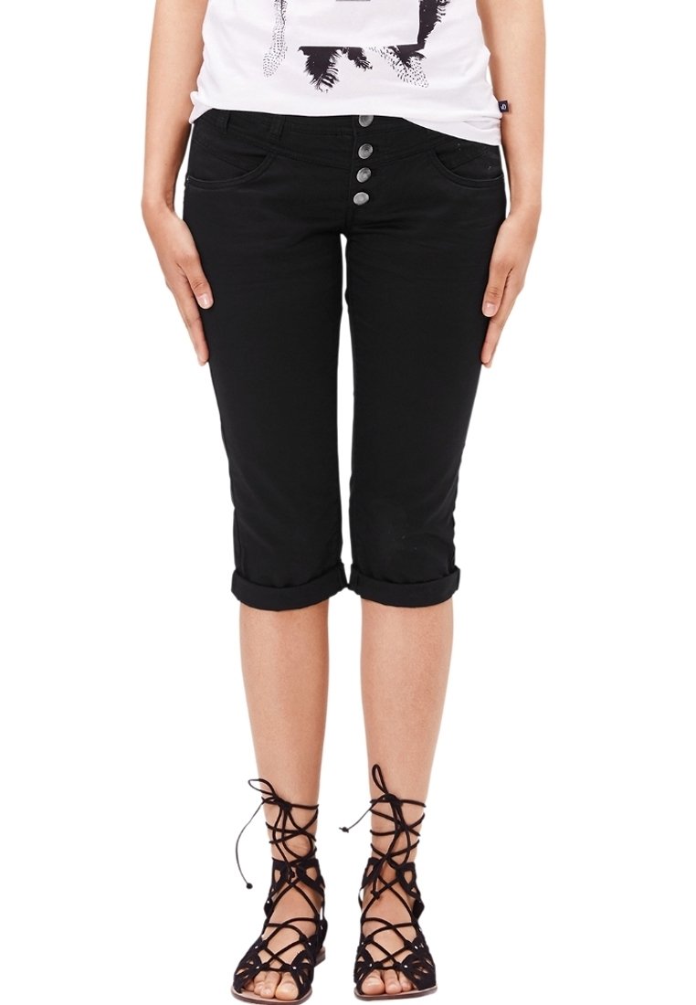Los pantalones capri negros presentan un diseño ajustado con dobladillos enrollados, cinco bolsillos y acentos de botón metálico en la tapa frontal.