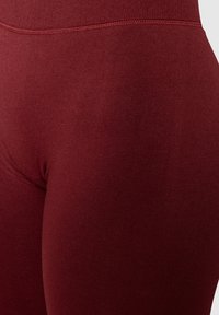 Leggings borgogna realizzati in un tessuto elasticizzato e testurizzato, con una vita alta, caratterizzati da una superficie liscia e un design senza cuciture.