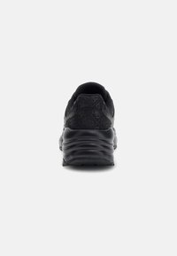 Zapatilla negra con un diseño texturizado, cuello acolchado y una suela de goma gruesa y ondulada para mayor soporte.