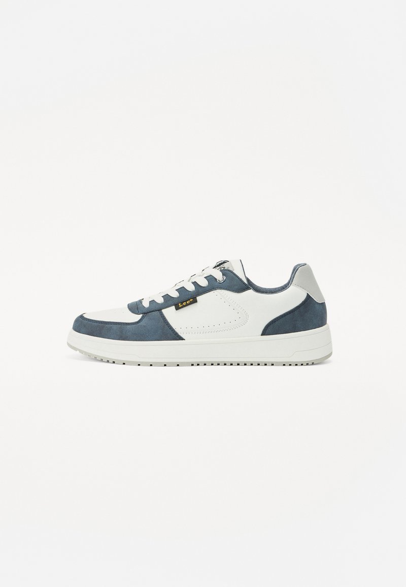 Zapatillas con una mezcla de ante azul marino y cuero blanco. Presentan una suela blanca, detalles perforados y una etiqueta negra en el costado.