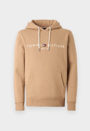 Beige hettegenser laget av bomullsblanding med frontlomme, snøring på hetta og hvit logo tekst: "TOMMY HILFIGER EST. 1985".