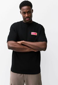 Mustast puuvillast lühikeste varrukatega t-särk, mille vasakul rinnal on v�ärvikas "MARVEL" logo plaastriga. Lihtne, lõdvestunud lõikega disain.