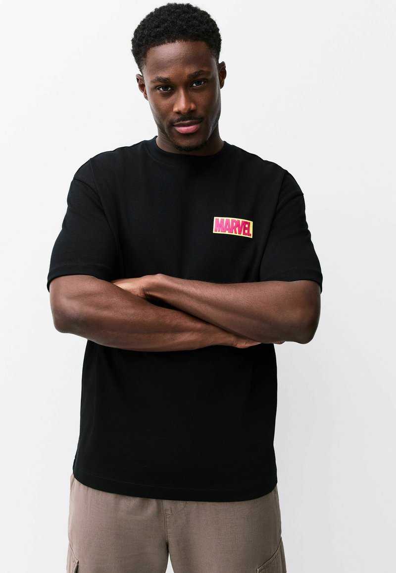 Fekete rövid ujjú pamut póló, a bal mellrészen színes "MARVEL" logóval ellátott folttal. Egyszerű, laza szabású design.