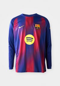 Duga rukava nogometna majica s plavim i crvenim vertikalnim prugama, Nike logo, crest Barcelone i kružni Spotify logo u sredini.