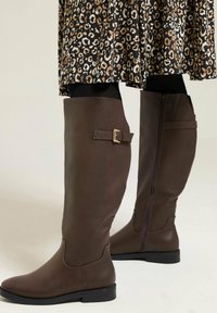 Stivali al ginocchio in pelle marrone dal design elegante, con un accentuato cinturino e una zip laterale per una facile vestibilità.