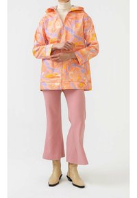 Farverig regnjakke med et abstrakt mønster i orange, lilla og gul; letvægtsstof, lynlås foran, stor hætte og løs pasform.