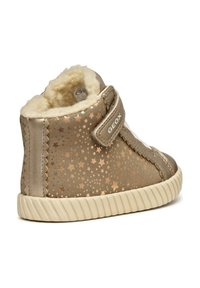 Scarpa beige in velluto a metà altezza con motivo a stella metallica, morbida fodera in pile crema e cinturino in Velcro. Suola in gomma testurizzata, punta rotonda.