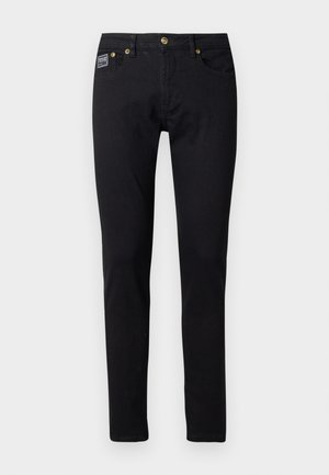 Black denim jeans with a slim fit, featuring gold-tone hardware, five pockets, and a small brand label on the right pocket.