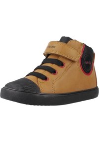 Zapato alto de cuero marrón con punta y suela de goma negra, con cierre de cordones y velcro, que presenta acentos rojos y un logo en el lateral.
