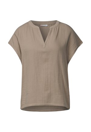Beżowa bluzka z krótkim rękawem, mająca dekolt w kształcie litery V, wykonaną z miękkiego, teksturowanego materiału z delikatnymi zagnieceniami oraz luźnym krojem. Dolna część jest zaokrąglona.