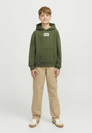 Sudadera verde con un bolsillo frontal y etiqueta de logo, combinada con pantalones cargo beige y zapatillas. La sudadera tiene un corte relajado y capucha ajustable.