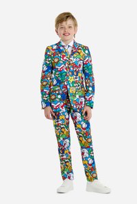 Bunter Kinderanzug mit einem vollständigen Muster von Cartoonfiguren, hauptsächlich in Blau, Rot, Grün und Gelb. Weißes Hemd und Schuhe.