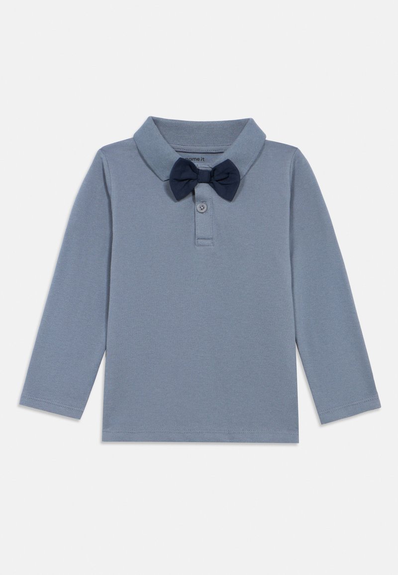 Ανοιχτό μπλέ μακρυμάνικη μπλούζα πόλο με ναυτικό μπλέ παπιγιόν συνημμένο στο κολάρο, τοποθετημένο επίπεδα σε λευκό φόντο.