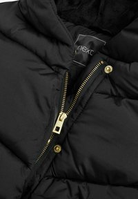 Doudoune noire avec une fermeture éclair dorée brillante et un bouton-pression. Comprend une doublure noire douce et une étiquette avec le nom de la marque "next."