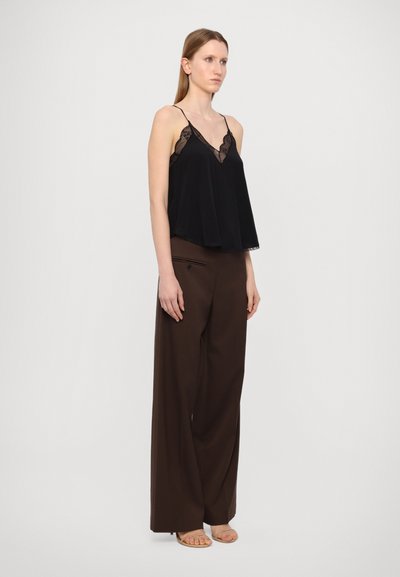 Zwarte camisole top met kant, gecombineerd met een wijde bruine broek. De set heeft spaghettibroodjes en een losse silhoutte.