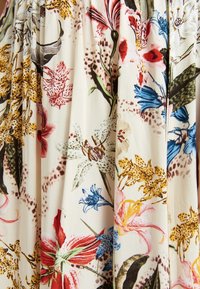 Bloemenstof met een crèmekleurige achtergrond en kleurrijke illustraties van verschillende bloemen, waaronder lelies en orchideeën, in lumineuze tinten.